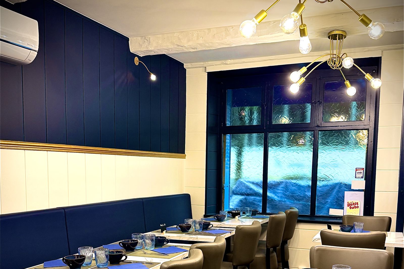 La salle rénovée de La Bolée : lambris bleu nuit, filet doré, suspensions dorées et banquettes bleues